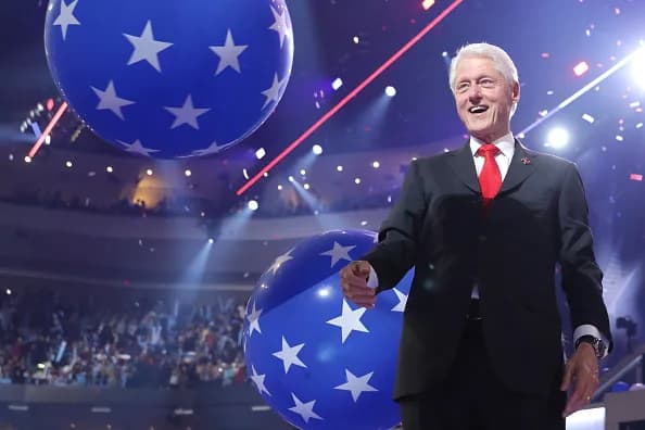 Former US President Bill Clinton plays with balloons on stage at the...