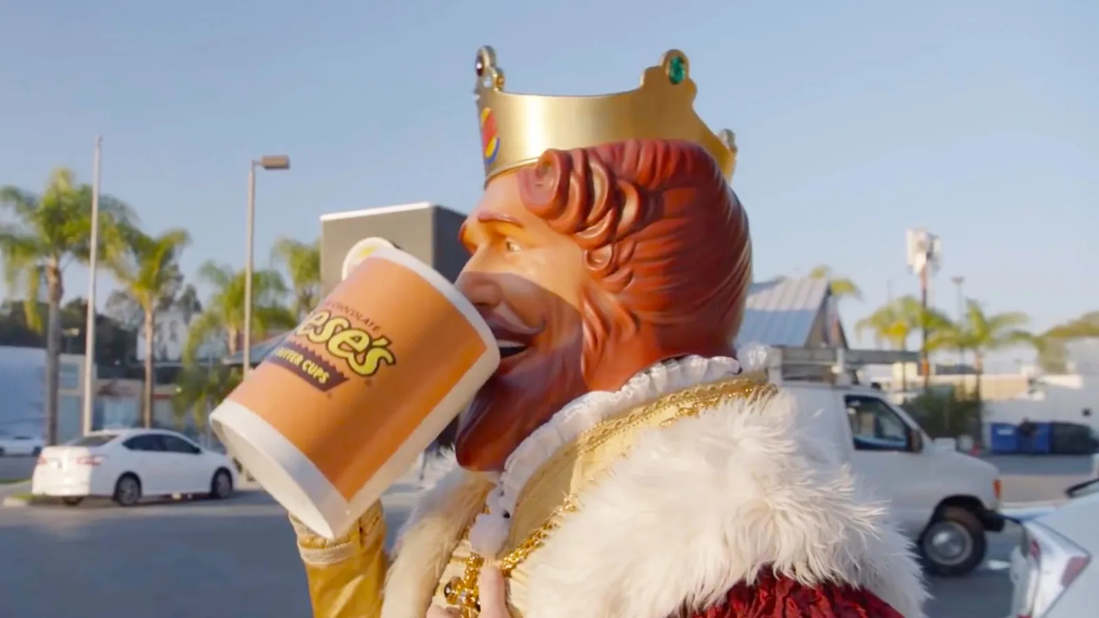 Frame from Whopper Neutrality showing the King drinking from an oversized Reese's mug.