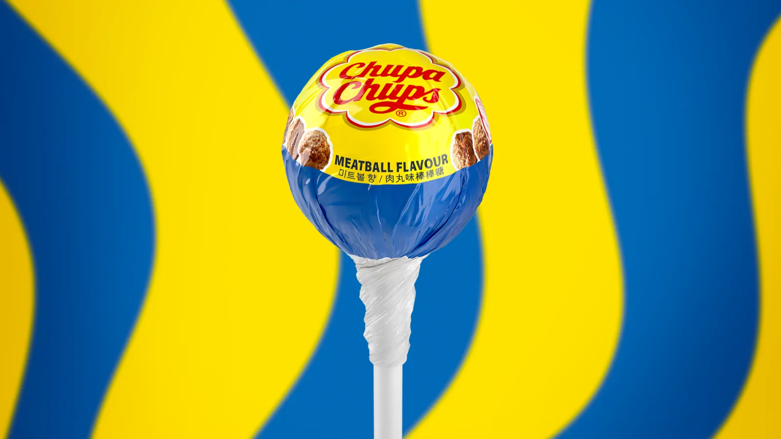 Meatball-flavored IKEA and Chupa-Chups lollipop in front of abstract blue and yellow background