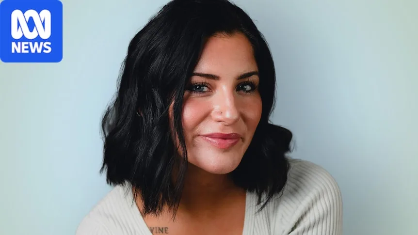 Lauren smiles as she looks to the camera in a headshot wearing a white top, with her short dark hair down.