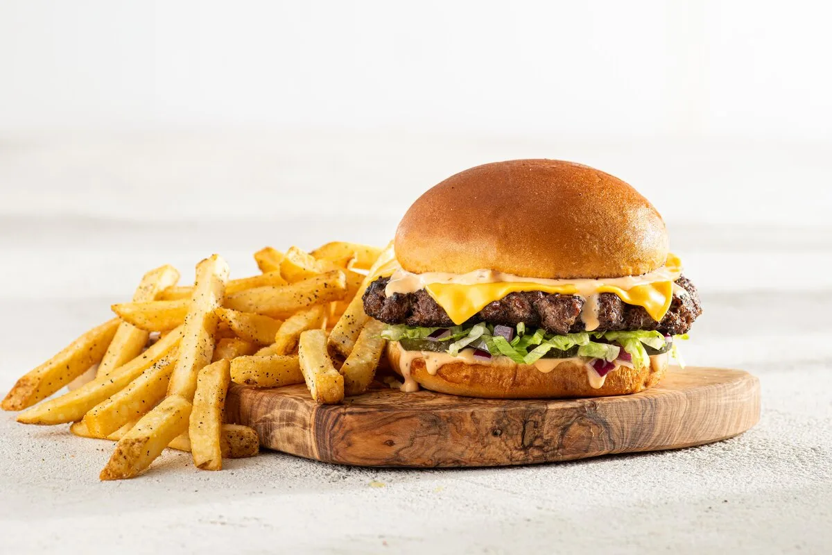 Big Smasher burger and fries on a wooden board, from the official burger menu.