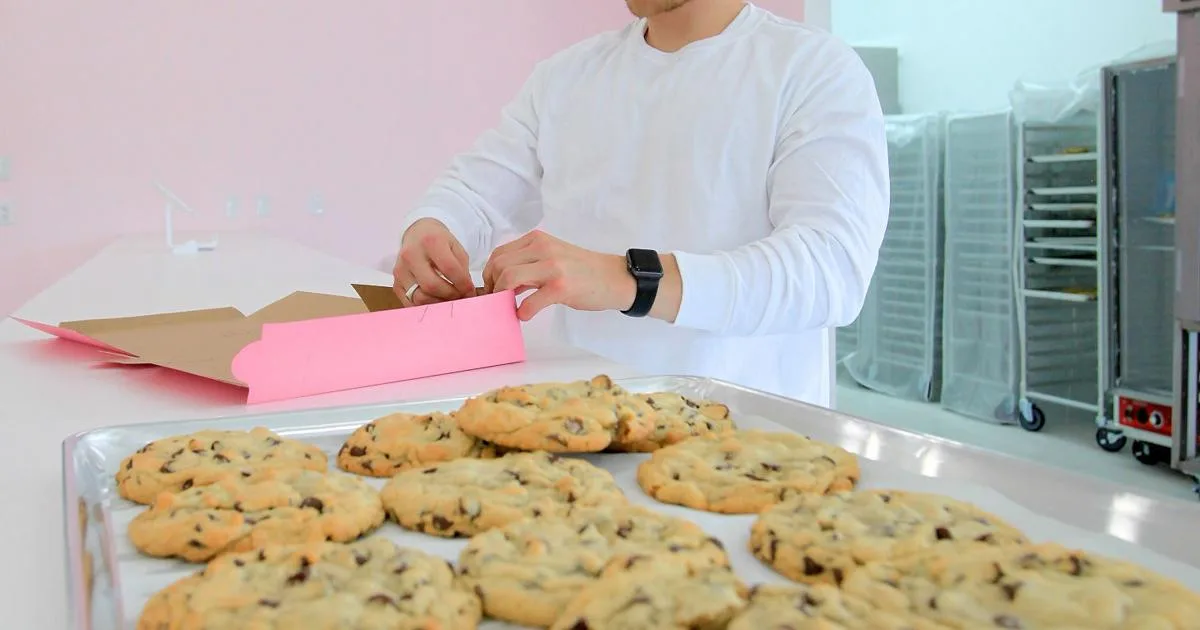 A Crumbl employee boxing cookies in the chain's pink packaging.
