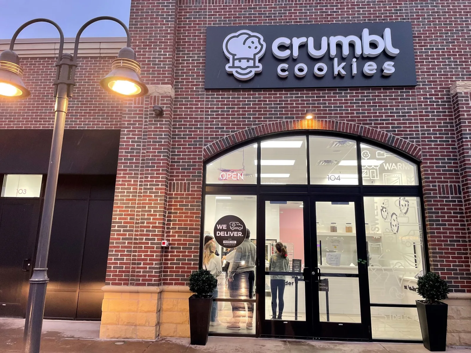 A Crumbl Cookies storefront at dusk.