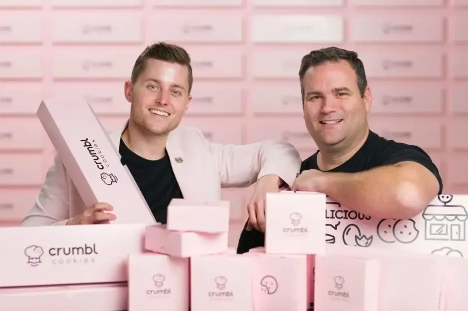 Crumbl co-founders Jason McGowan and Sawyer Hemsley with pink Crumbl boxes.