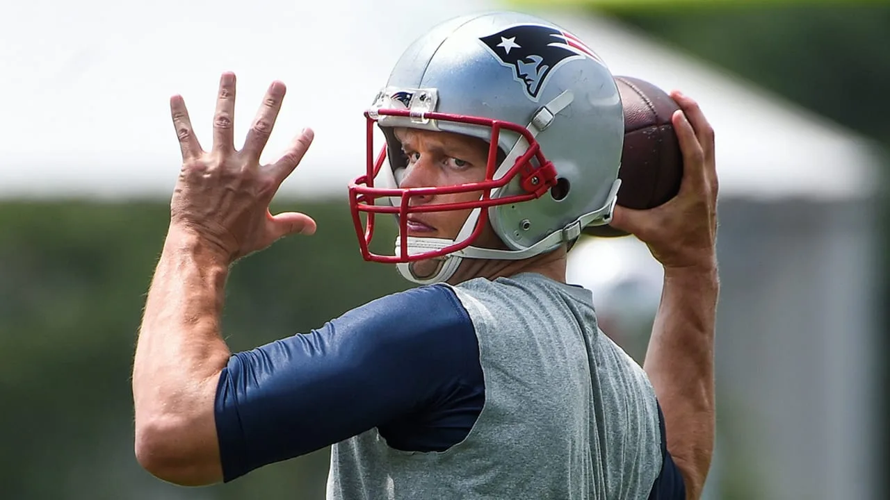 Tom Brady throwing a pass in a Patriots practice jersey