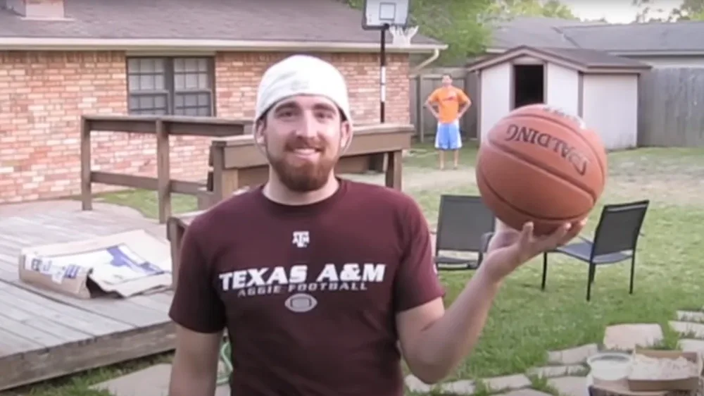 A Dude Perfect member in a Texas A&M T-shirt with a basketball