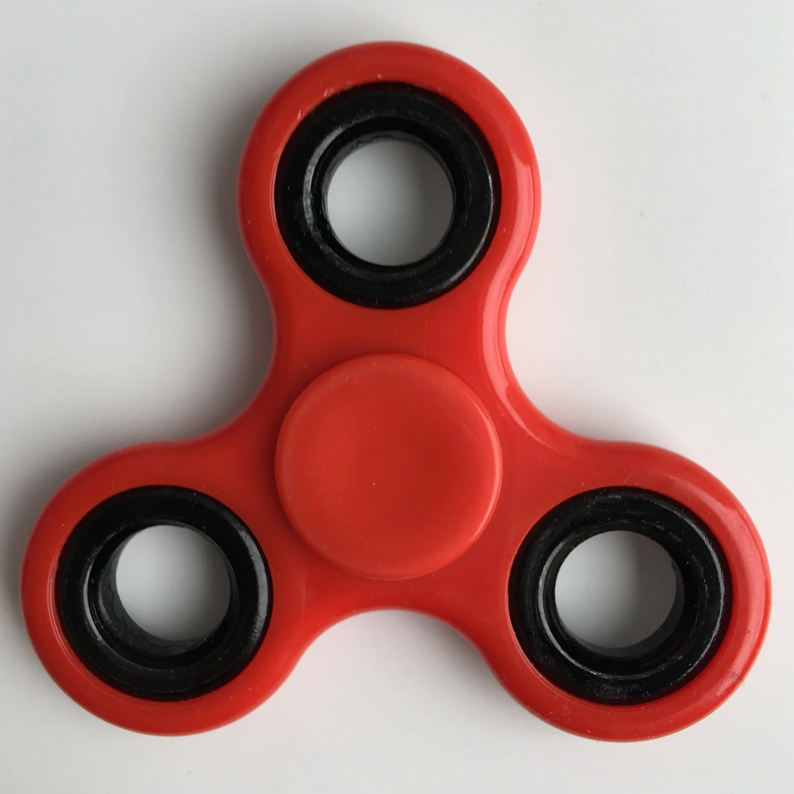 A red three-pronged fidget spinner, photographed May 28, 2017. CC0.