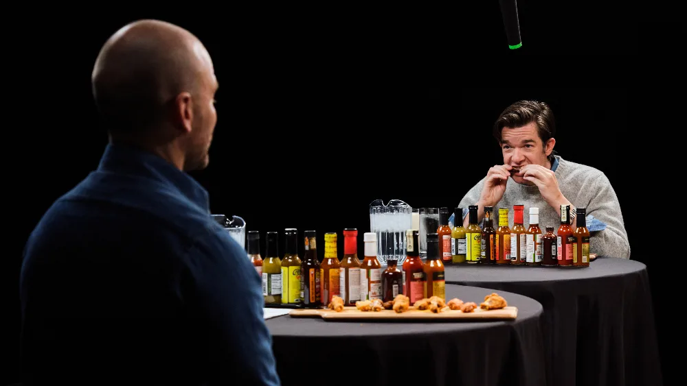 Sean Evans interviewing John Mulaney over a row of hot sauces.