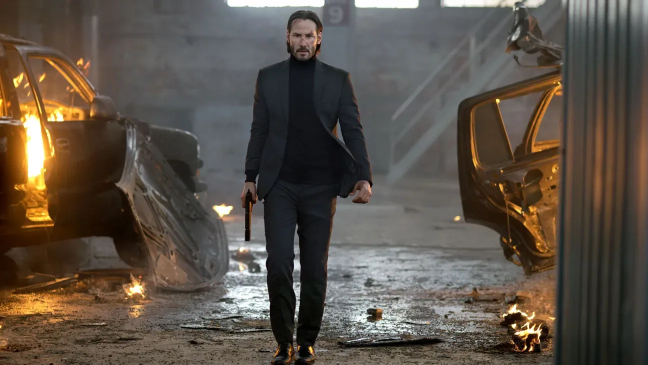 John Wick walks through a wrecked garage