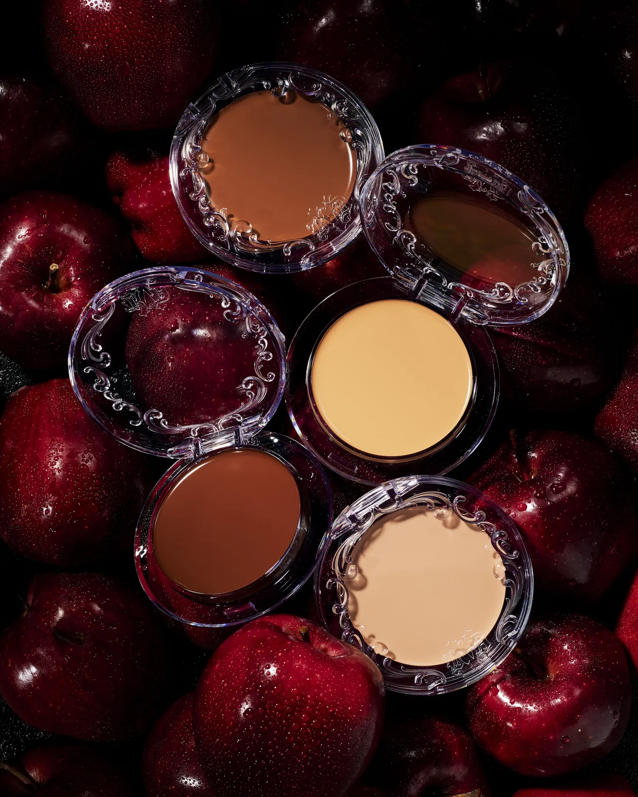 Good Apple foundation balm compacts on red apples, from KVD Beauty’s Feelunique launch release.