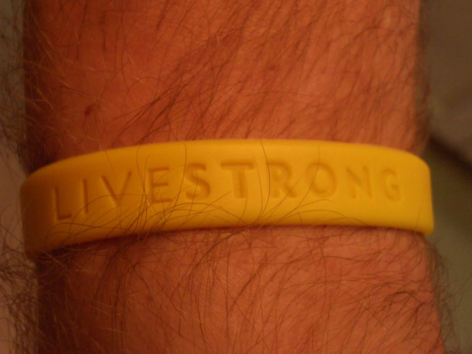 Yellow Livestrong wristband worn on a wrist; Sherool, CC BY-SA 3.0.