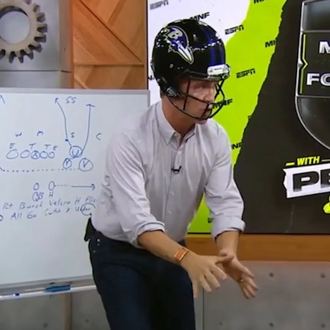 A Manning brother in a helmet at the whiteboard during a ManningCast