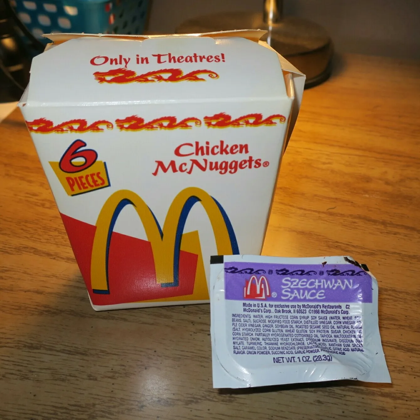 An original 1998 Szechuan sauce packet with a Mulan McNuggets box