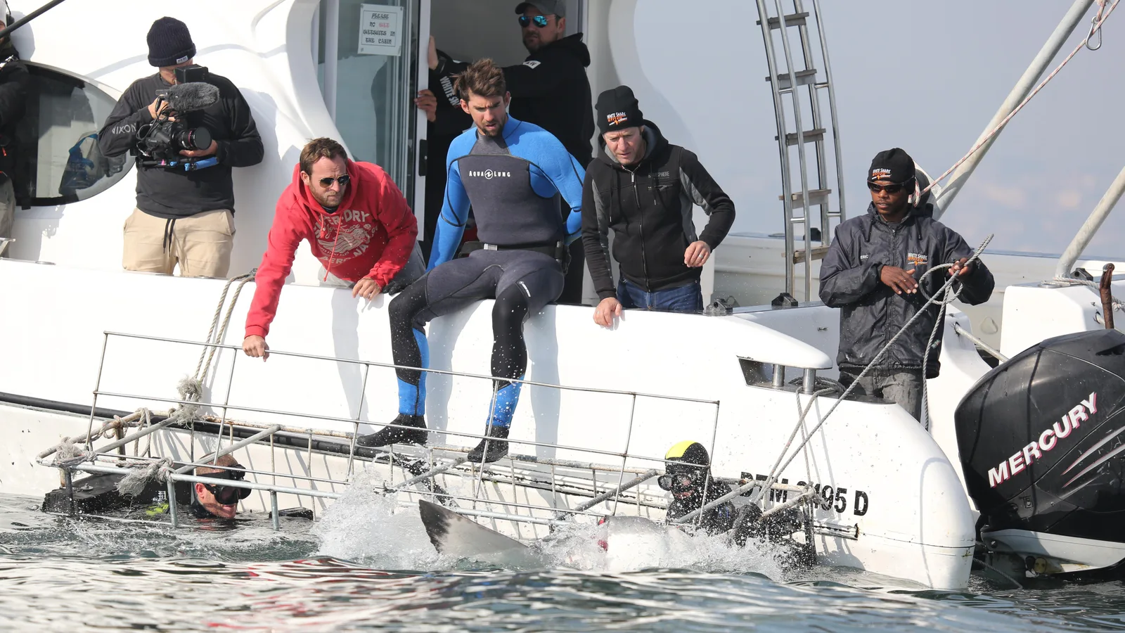 The Shark Week crew lowering a shark cage off a boat