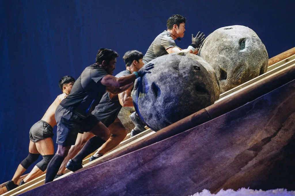 Contestants push giant boulders up a ramp in Physical: 100
