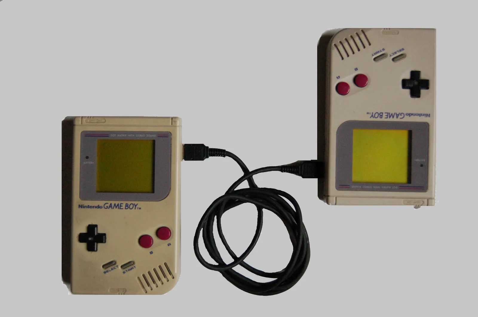 Two original Game Boys joined by a link cable, the way players traded Pokémon