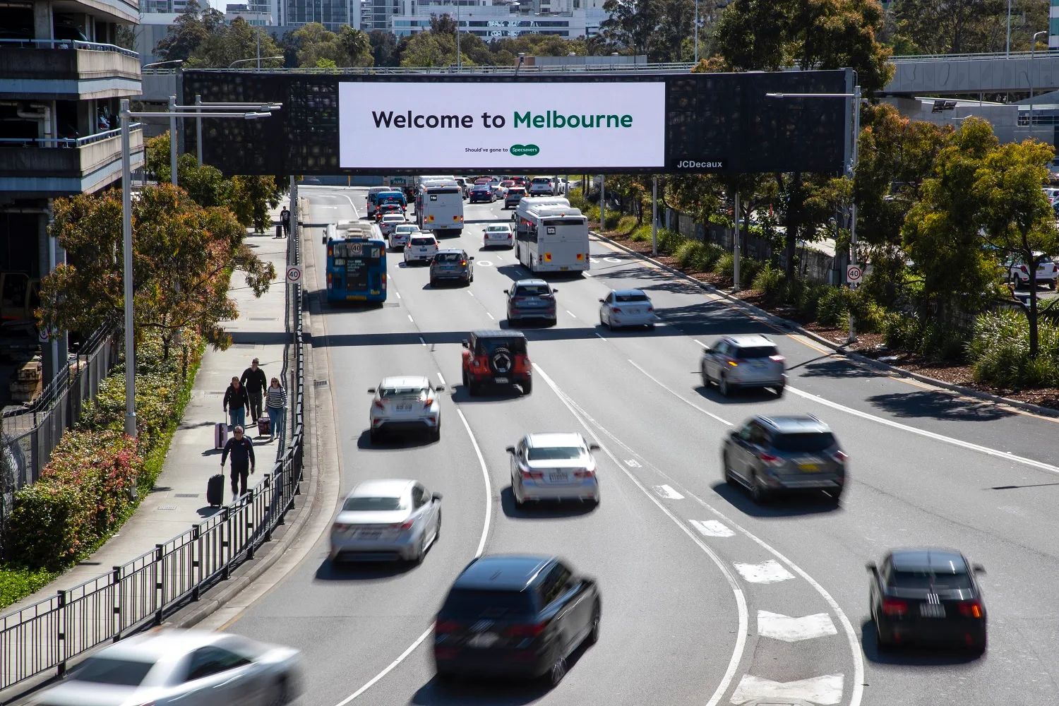 Specsavers Welcome to Melbourne billboard on a road at Sydney Airport.