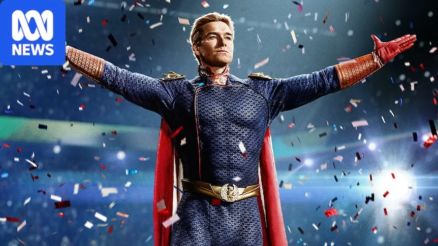 A blond man in a superhero outfit holds his arms out as confetti rains down
