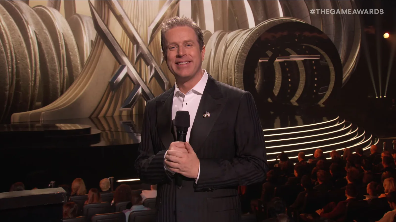 The Game Awards 2025 livestream screenshot of host Geoff Keighley holding a microphone with the stage in the background