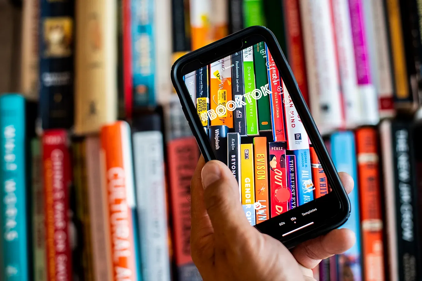 A phone showing TikTok in front of bookshelves