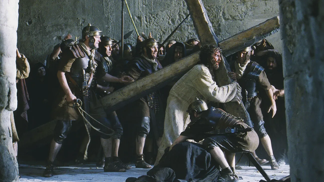 Jim Caviezel as Jesus carrying the cross among Roman soldiers, in a still from the film.