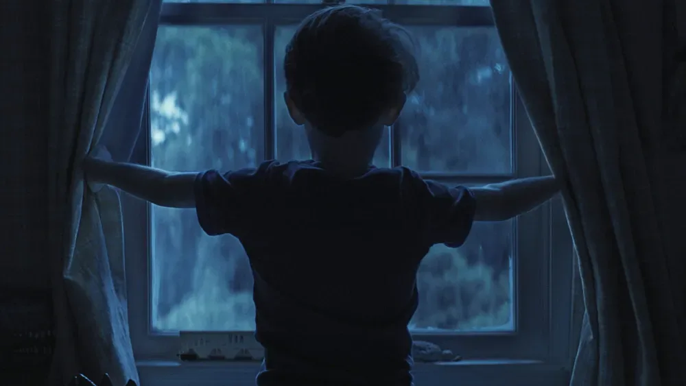 A boy at a window, seen from behind, in Weapons