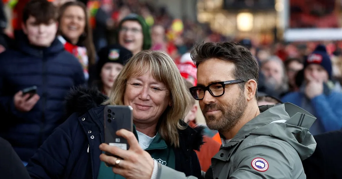 Wrexham co-owner Ryan Reynolds poses with a fan before the match. Reuters