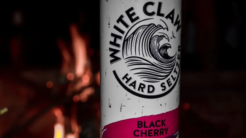 A Black Cherry White Claw can by a fire